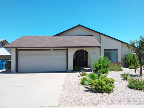 a white house with a garage door and a gravel driveway