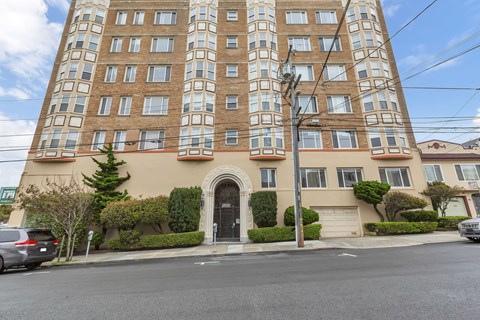 A tall apartment building with a brown facade and a black door.