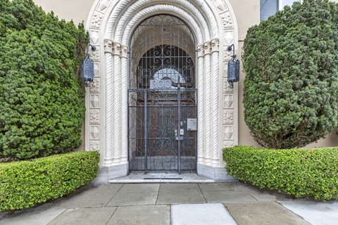 A large, ornate gate is the centerpiece of a well-manicured entrance.