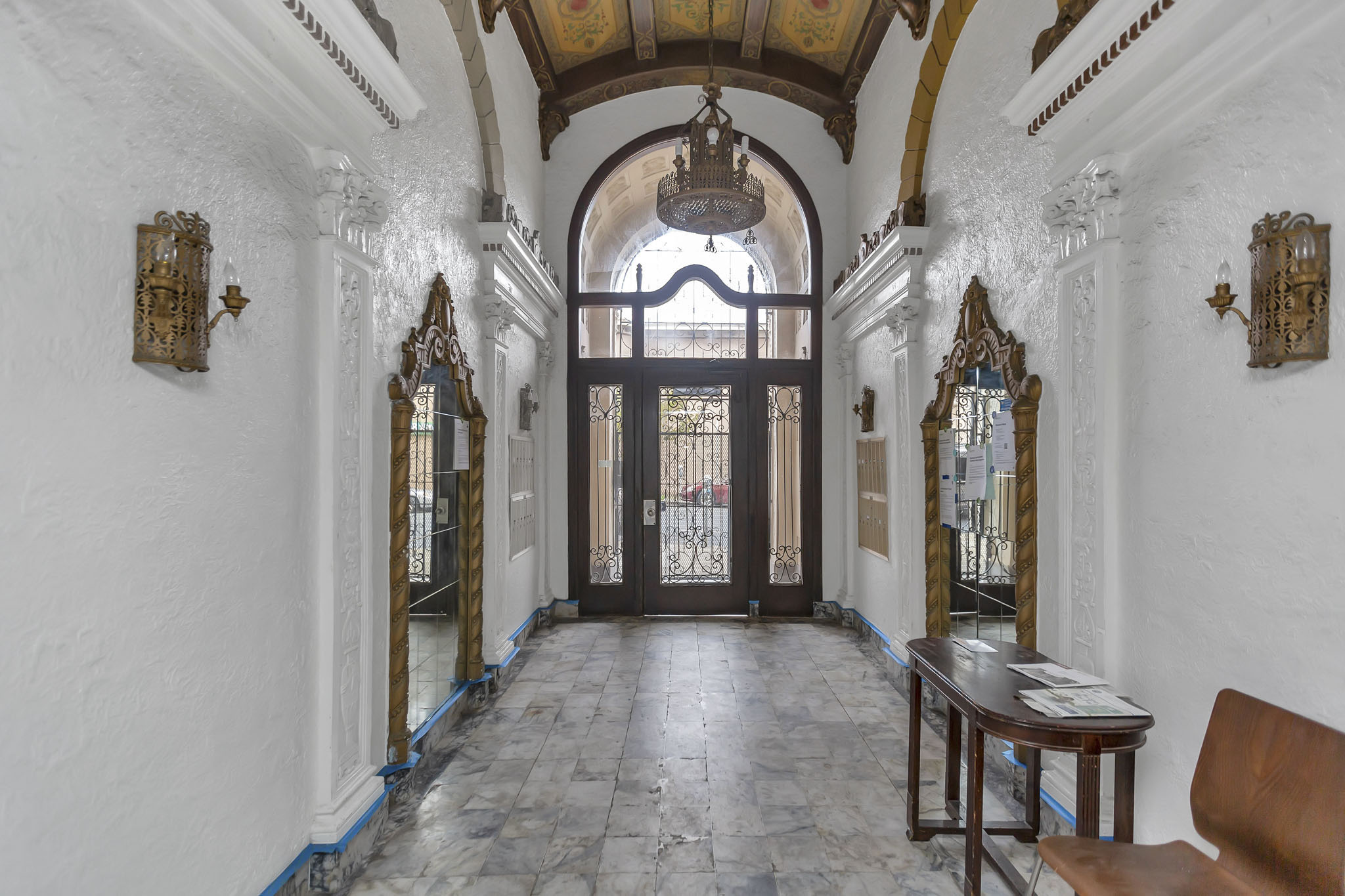 A hallway with a wooden bench and a table with a chandelier hanging from the ceiling.