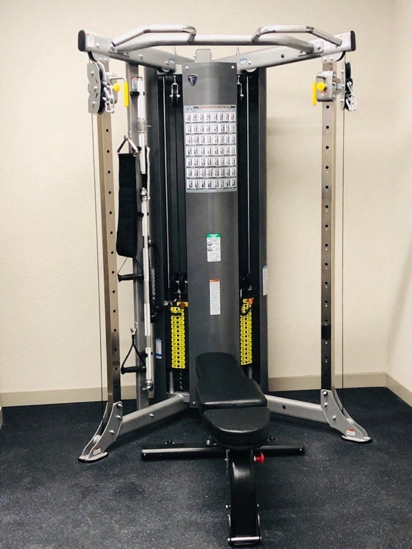 a gym set up in a room with a chair and weights