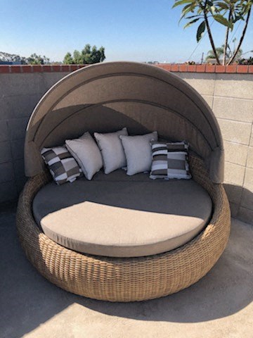 a round rattan chair with pillows on a patio