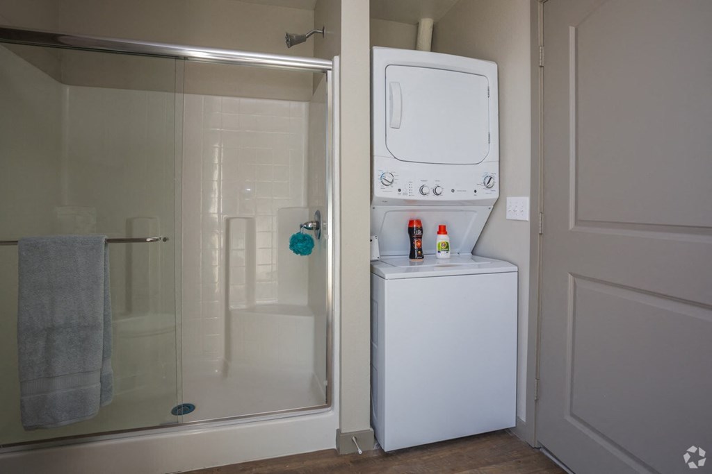 a small bathroom with a washer and dryer next to a shower
