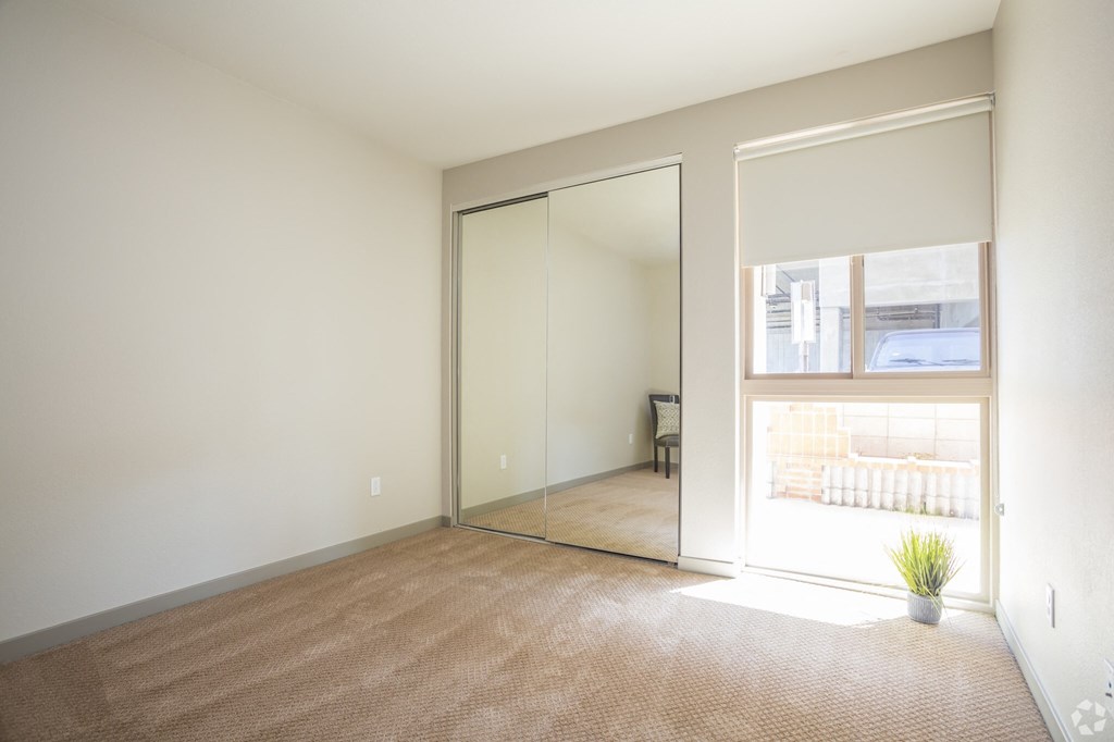 an empty living room with a large window and a door to a bedroom