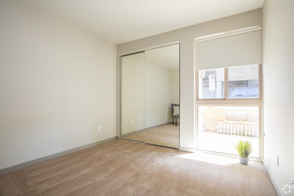 an empty living room with a large window and a door to a bedroom