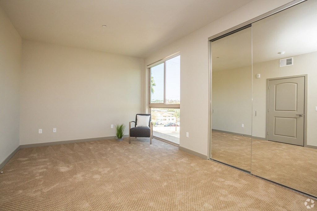 an empty living room with a large window and a mirrored door