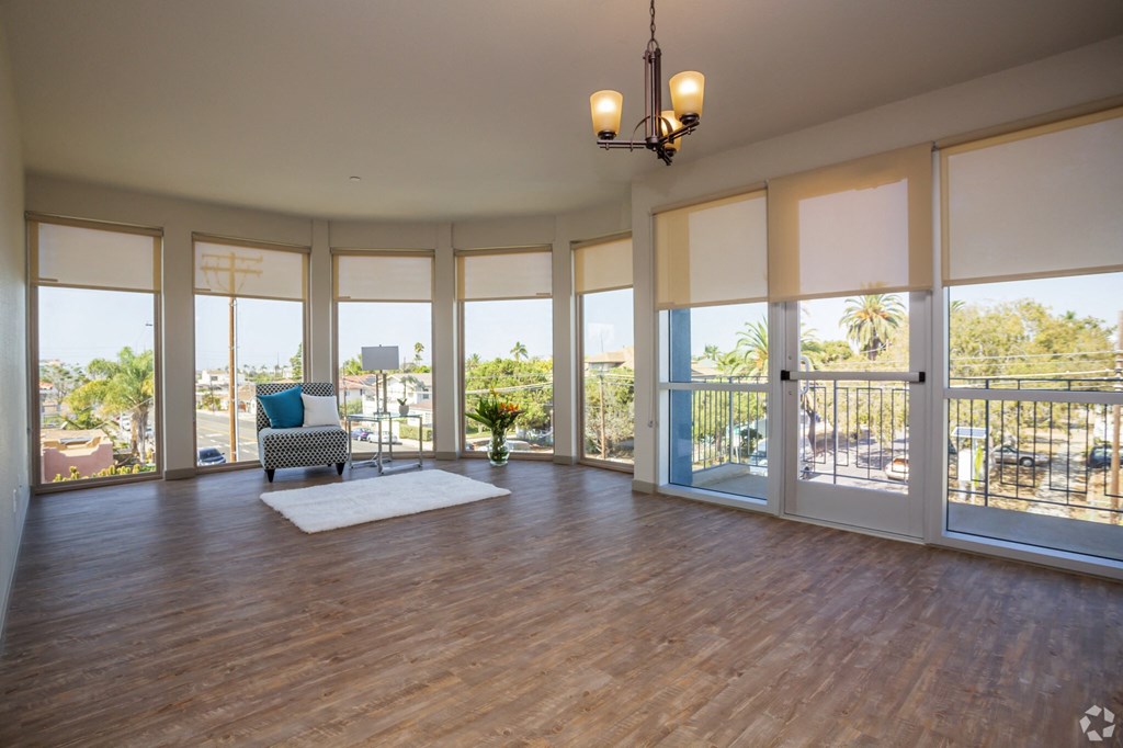 an empty living room with a hard wood floor and large windows