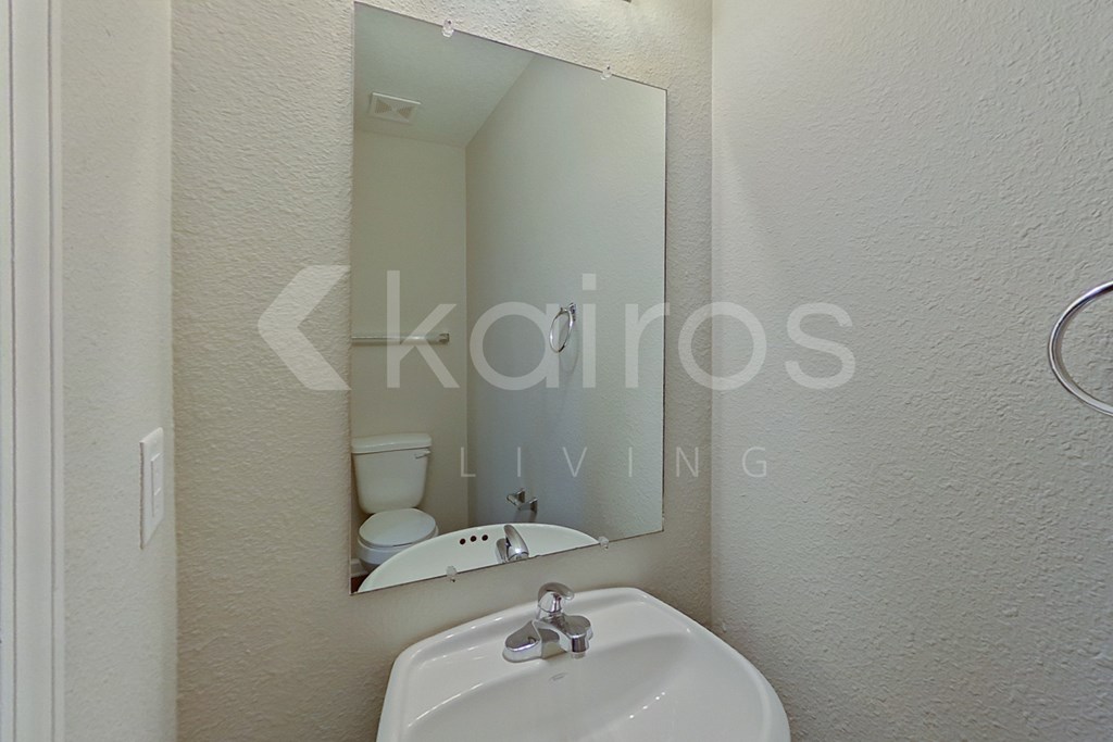 A white sink is mounted under a mirror in a bathroom.