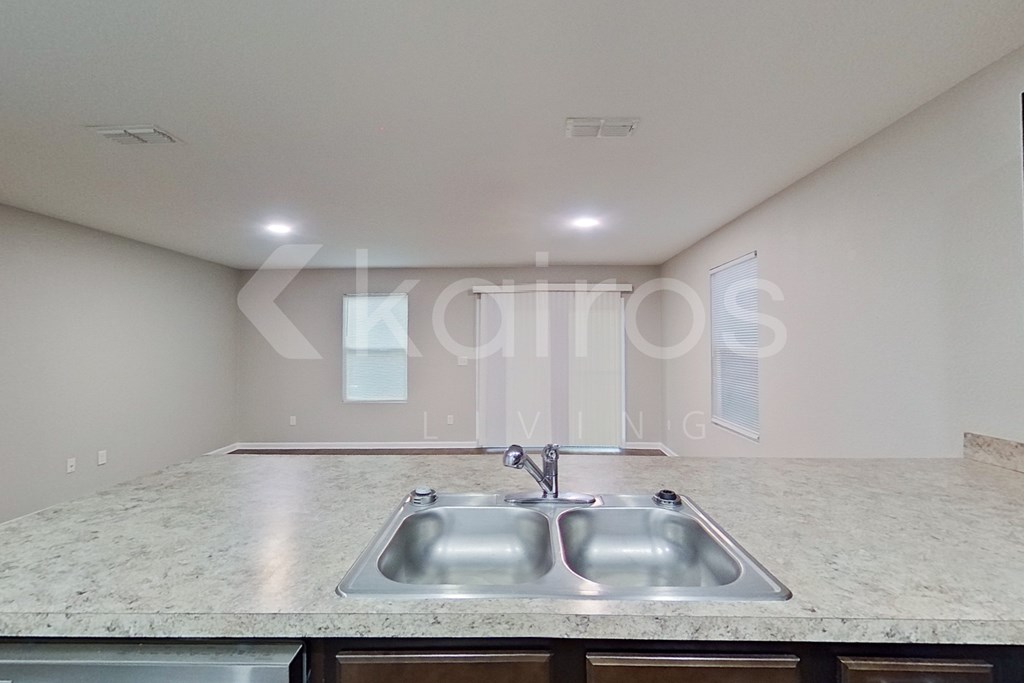 A kitchen with a granite countertop and a double sink.