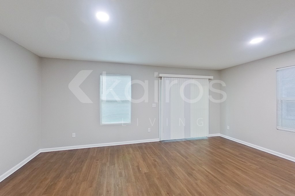A room with wooden flooring and a window with blinds.