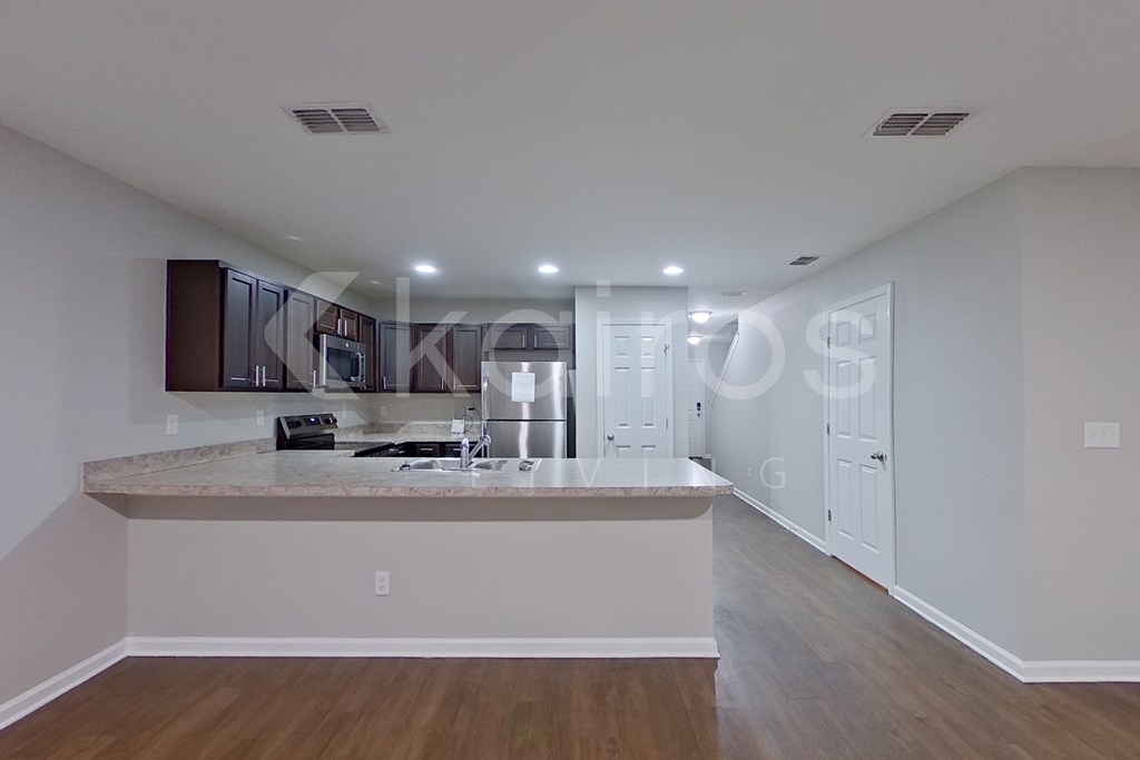 A kitchen with a granite countertop and wooden flooring.