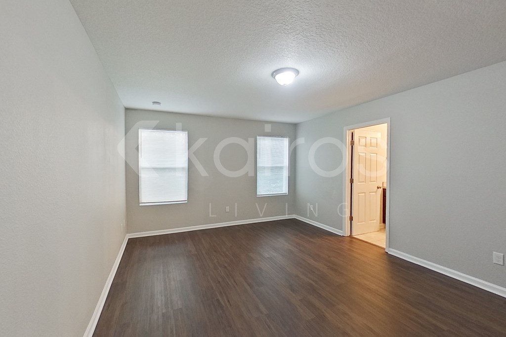 A room with wooden flooring and a door on the right side.