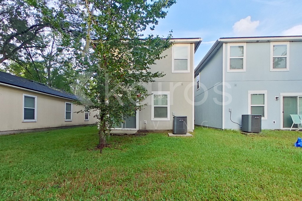 A tree is in front of a house with a blue sky in the background.