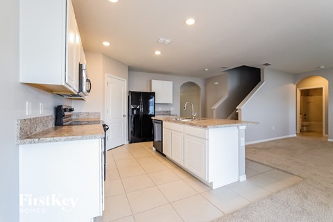A kitchen with white cabinets and a granite countertop.
