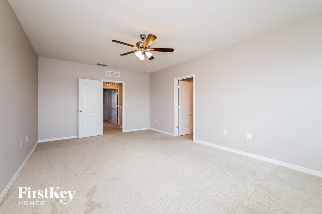 A spacious room with a ceiling fan and two doors.