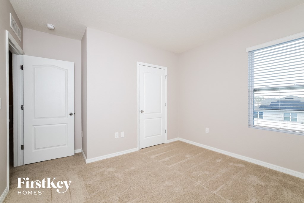 A room with two doors and a window with a view of a building.