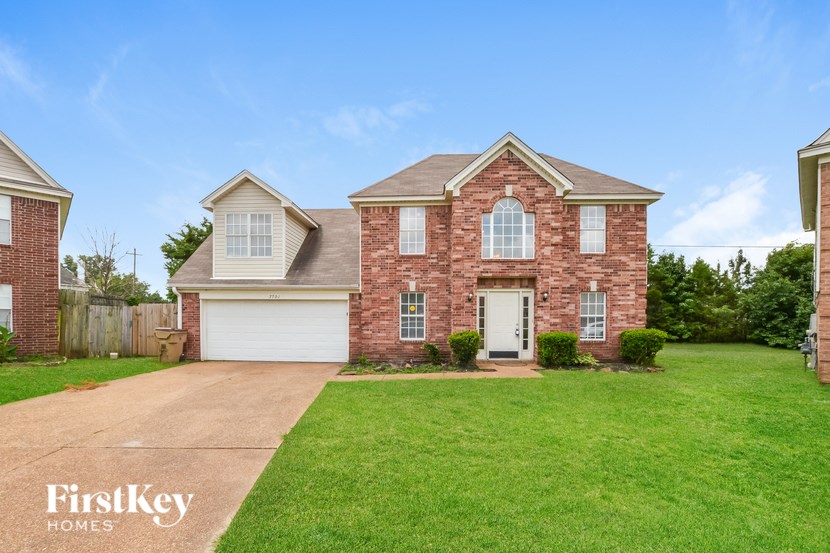 A brick house with a white garage door and a green lawn.
