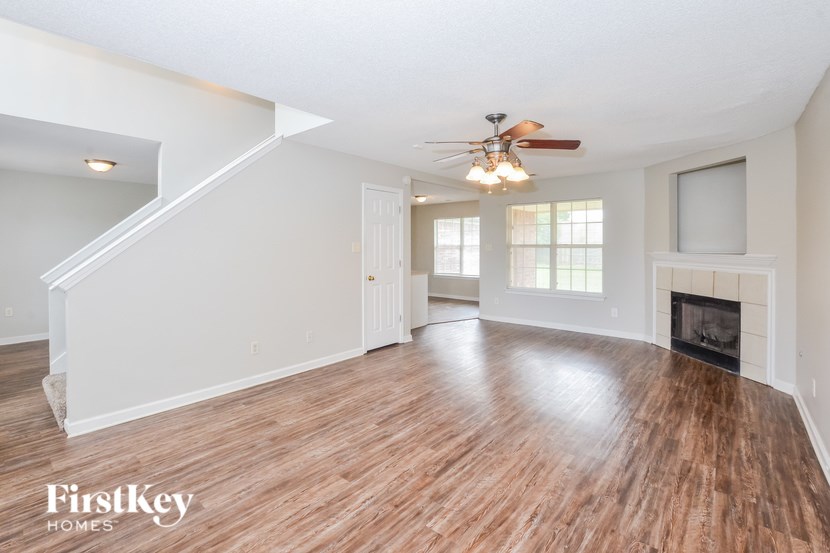 A spacious living room with wood flooring and a fireplace.