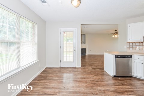 A kitchen with white cabinets and a wooden floor.
