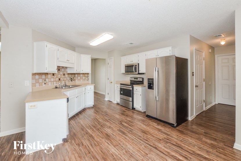A kitchen with wooden floors and white appliances.