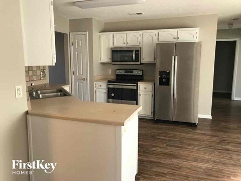 A kitchen with a refrigerator, oven, and microwave.