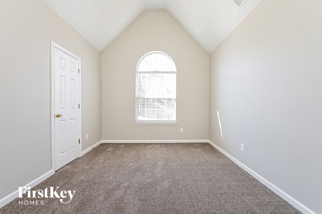 an empty bedroom with carpet and a window