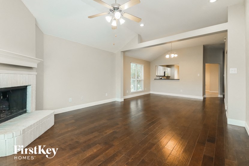 a empty living room with a fireplace and a ceiling fan