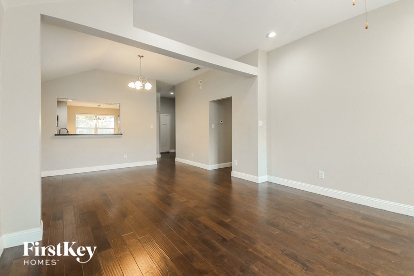 the living room and dining room with wood flooring and white walls