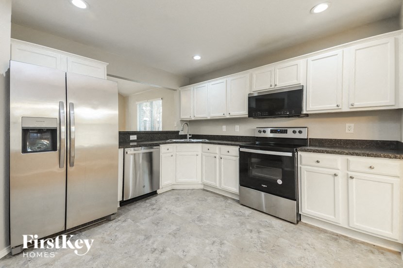 a white kitchen with stainless steel appliances and white cabinets