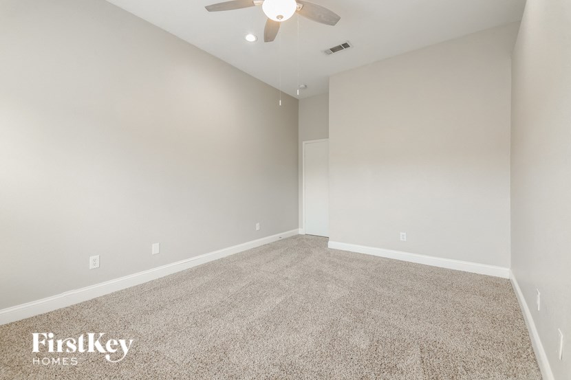 an empty living room with a ceiling fan and carpet