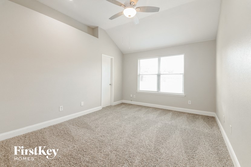 an empty living room with a ceiling fan and a window