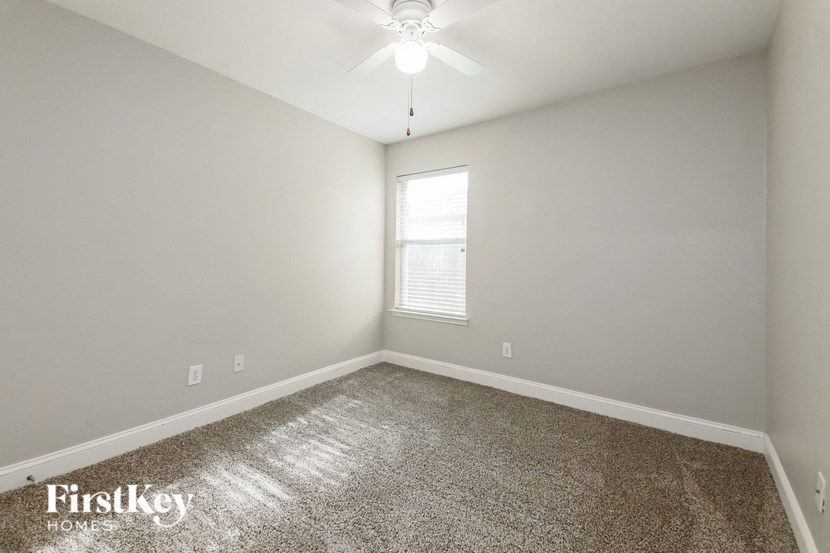an empty room with a ceiling fan and a window