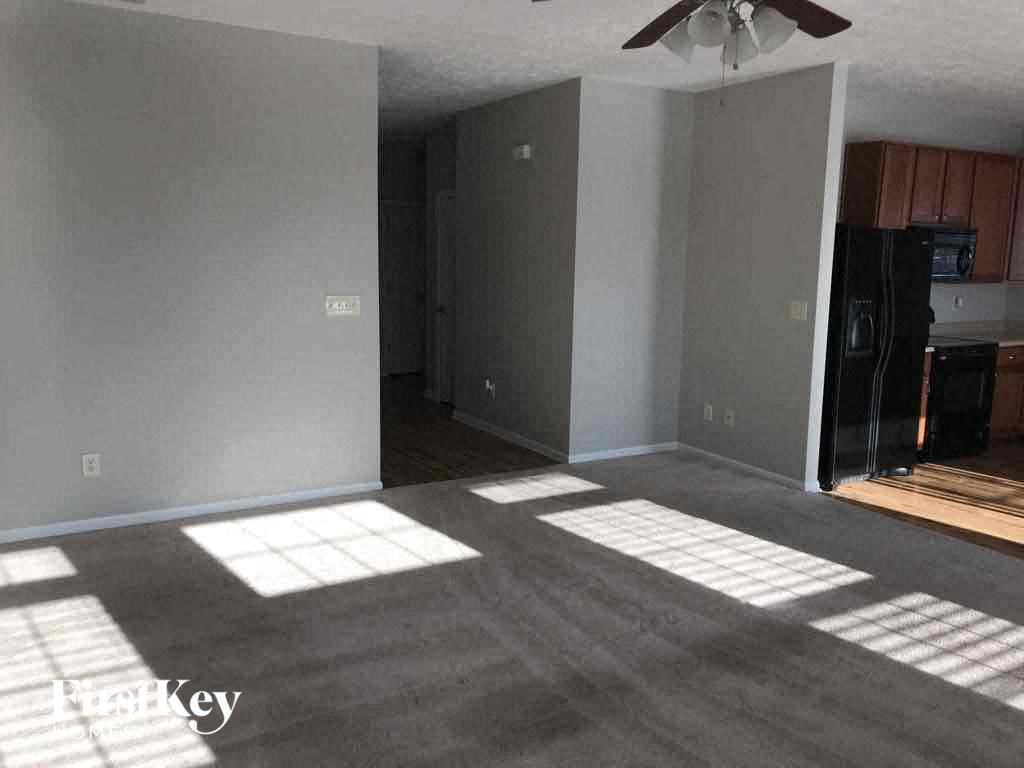 A room with a ceiling fan and a door leading to a kitchen.