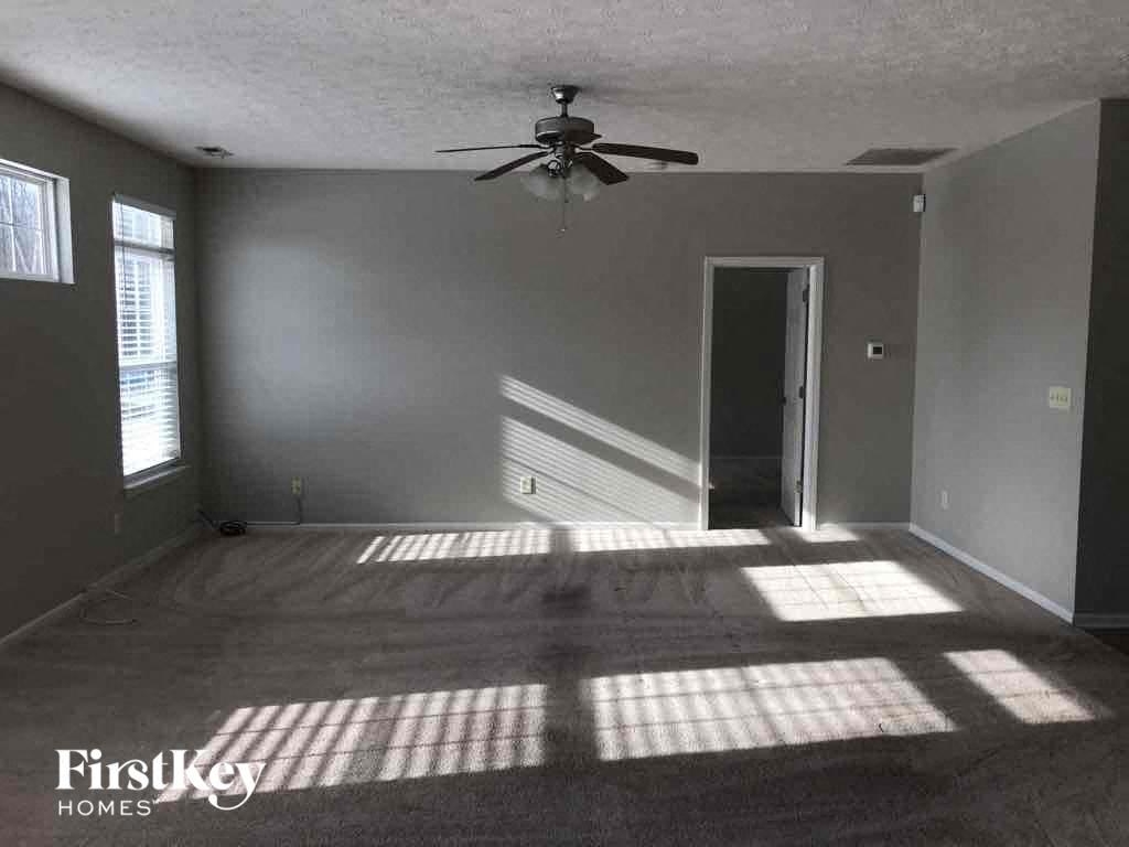 A room with a fan and a carpeted floor.