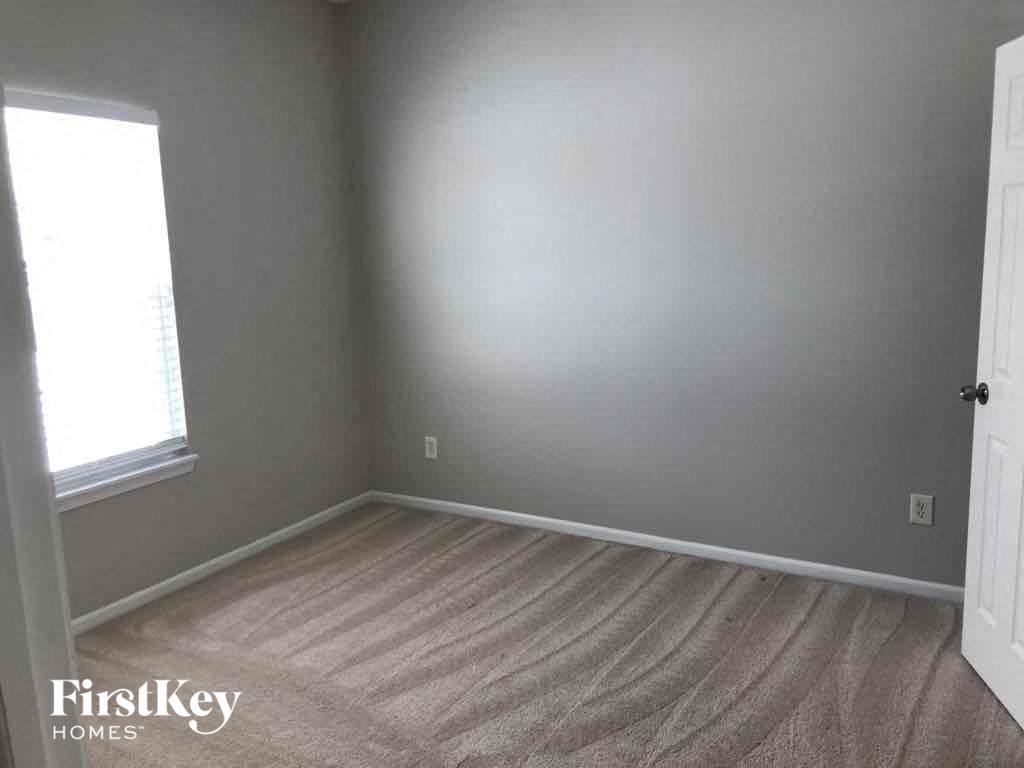 A room with a carpeted floor and a door on the right side.