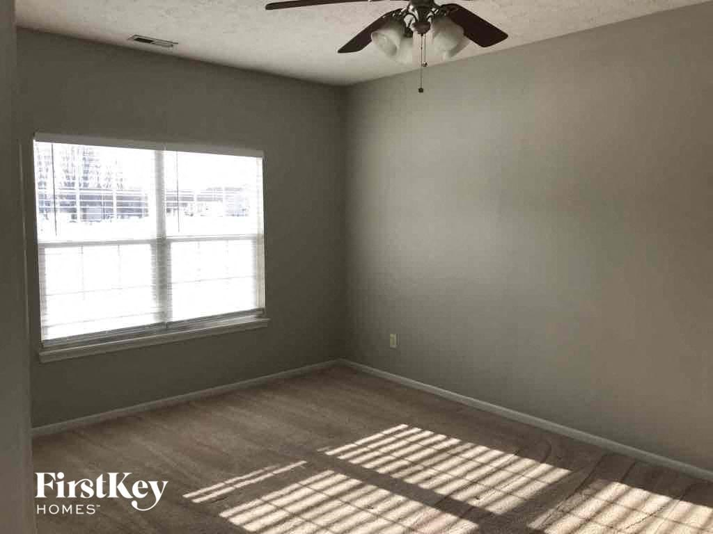 A room with a ceiling fan and a window letting in sunlight.