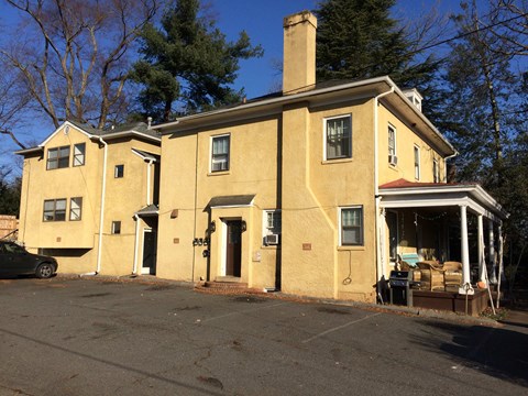 A yellow house with a black car parked in front.
