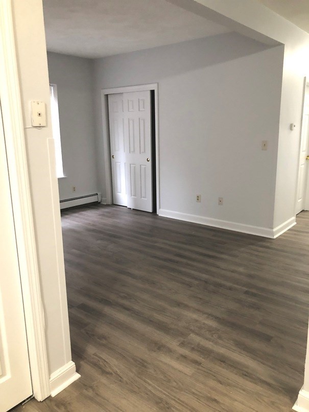 an empty living room with wooden floors and a white door