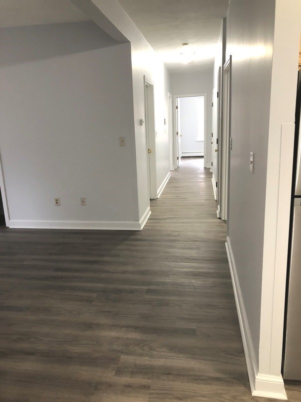 a hallway with wood flooring and white walls and a white door