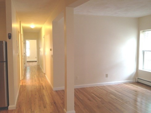 an empty living room and hallway with a wood floor