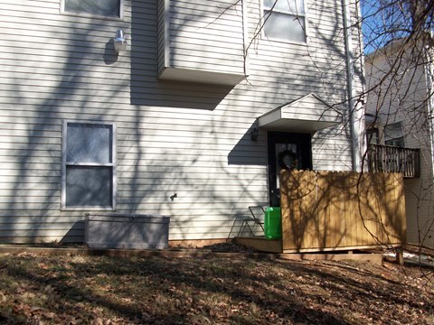 A house with a green trash can in front of it.
