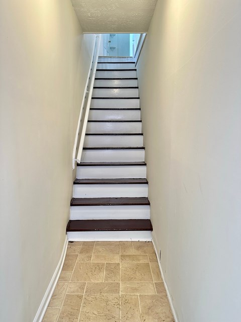 A staircase with white steps and a black striped runner.