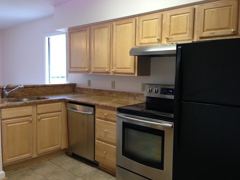 a kitchen with wooden cabinets and a black refrigerator