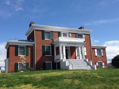 a red brick house on a hill with a blue sky