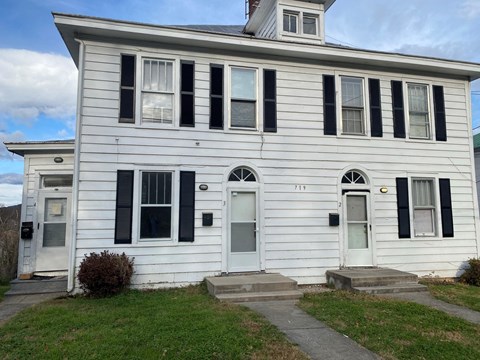 the front of a white house with black shutters