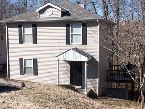 a white house with an open door on a hill