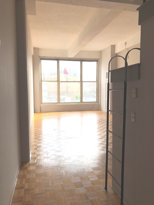 an empty living room with a window and a ladder