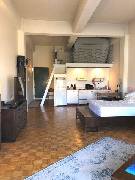 a room with a bed and a kitchen in it