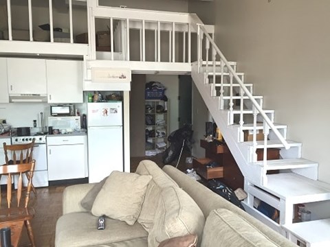 A living room with a couch and a staircase.