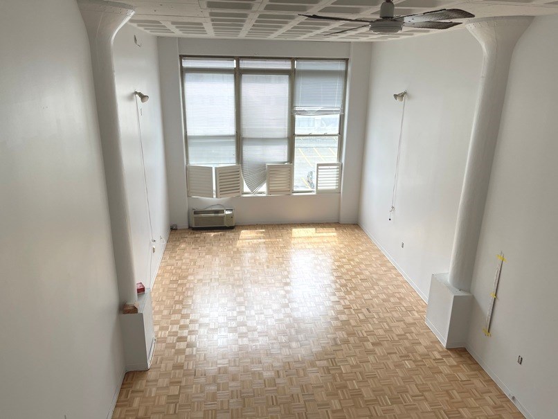 an empty room with a window and a wood floor